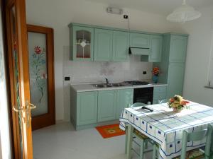 a kitchen with green cabinets and a table with chairs at Appartamento La Collinetta in Gonnesa
