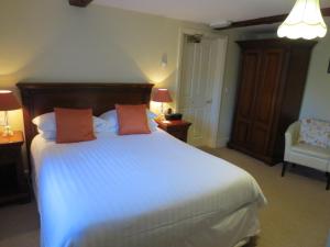 a bedroom with a large white bed with two orange pillows at Pack Horse Inn in Mellor