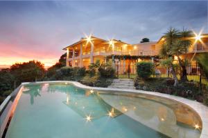 a large house with a swimming pool in front of it at River Rock Retreat in Maroochy River