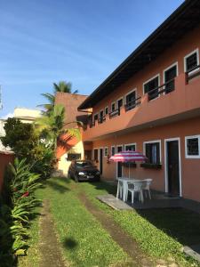 a patio with a table and an umbrella in front of a building at Pousada Refúgio D´Mar in Ubatuba