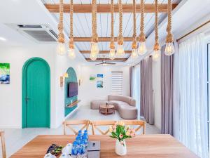 a living room with a table and a green door at Novaworld Phan Thiết - Alala Stay in Bình Sum