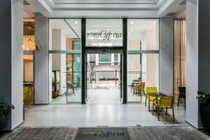 a lobby with glass doors and tables and chairs at Athens Cypria Hotel in Athens