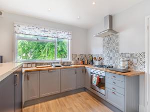 a kitchen with white cabinets and a window at Leehaven in Torquay