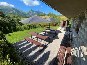 two picnic tables and an umbrella on a patio at U Milušky in Ždiar
