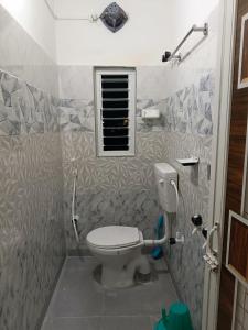 a bathroom with a toilet and a window at Bridhi Guest House in Siliguri