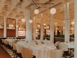 a dining room with white tables and chairs and chandeliers at The Telegraph Hotel - The Leading Hotels of the World in Tbilisi City