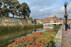 a river in a city with a bridge and flowers at Spacious apartment in heart of Tonbridge in Tonbridge +3 photos
