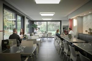 people sitting at tables in a restaurant with tables and chairs at bfwhotel und Tagungszentrum in Nuremberg