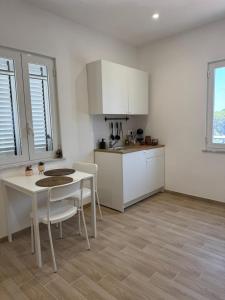 a kitchen with a table and white cabinets and a table and chairs at Casette in centro Por Siempre Cuatro House in Ischia