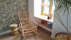 einem Schaukelstuhl aus Rattan in einem Zimmer mit Fenster in der Unterkunft Le Foyer Celtique in Ploërmel