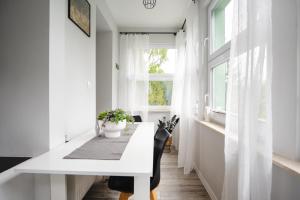 a white dining room with a white table and a window at Słoneczny Apartament in Duszniki Zdrój +12 photos