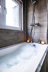 a bath tub in a bathroom with a window at The Sandford Park Townhouse 6 Bed Sleeps 12 Entire Apartment in Cheltenham +72 photos