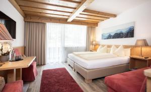 a hotel room with a bed and a desk and a window at Hotel Hubertus mit Summercard in Sölden +93 photos