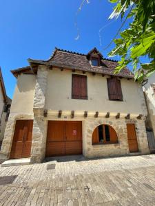 a house with two garage doors in a brick driveway at Studio La belle étape in Bretenoux