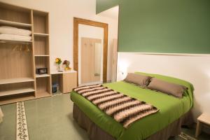 a bedroom with a green bed and a mirror at B&B Napolimilionaria Foria 242 in Naples