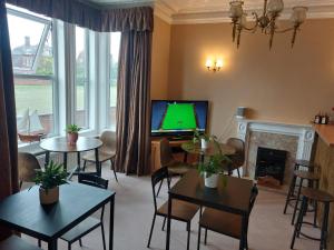 a living room with tables and a tv and a fireplace at The Chateau by MPH Holidays in Great Yarmouth