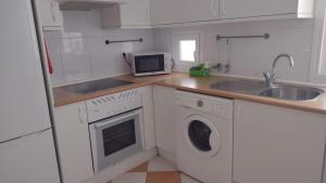 a white kitchen with a sink and a microwave at Tu refugio en Málaga, confort y ubicación perfecta in Málaga