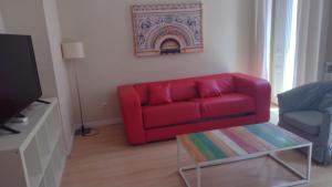 a living room with a red couch and a tv at Tu refugio en Málaga, confort y ubicación perfecta in Málaga