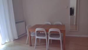 a dining room table with four white chairs around it at Tu refugio en Málaga, confort y ubicación perfecta in Málaga