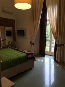 a bedroom with a green bed and a large window at B&B Napolimilionaria Foria 242 in Naples