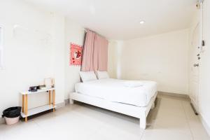 a white bedroom with a bed and a table at X Oh My Nap BTS Nana - โอ้ มาย แน็ป บีทีเอส นานา in Bangkok