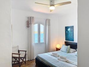 a bedroom with a bed with a ceiling fan and a window at Roca Fornells, Un rinconcito en el mar P107 in Fornells