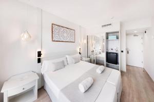 a white bedroom with a large white bed and a television at Hotel Ankaa - Adults Only in Porto Cristo