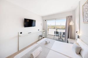 a white bedroom with a large bed and a balcony at Hotel Ankaa - Adults Only in Porto Cristo