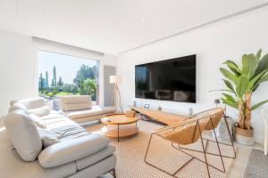 Una sala de estar con muebles blancos y un televisor grande. en Finca Son Set, en Inca
