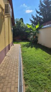 a brick sidewalk next to a yard with a house at Tuba Apartman in Kiskunhalas