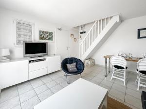 un salon blanc avec une télévision et une table dans l'établissement Maison cosy à deux pas du port et de la plage- idéale pour familles, à Dives-sur-Mer