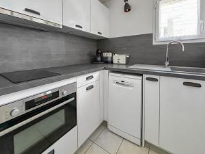 a kitchen with white cabinets and a sink and a dishwasher at Maisonnette cosy avec jardin - proche port et plage in Dives-sur-Mer