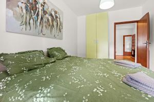 a bedroom with a bed with a green comforter at Apartments Kana in Pula