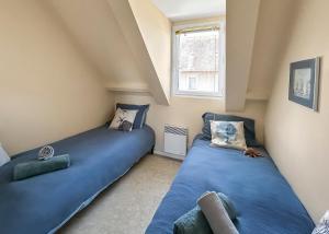 two blue beds in a room with a window at Maisonnette cosy avec jardin - proche port et plage in Dives-sur-Mer +6 photos