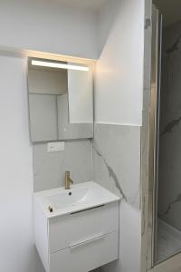 a white bathroom with a sink and a mirror at Paris 16, Lux Studio - Steps from metro 9! in Paris