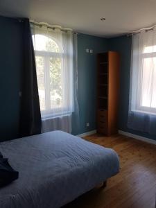 una camera da letto con pareti blu e un letto e due finestre di Villa Notre-Dame a Boulogne-sur-Mer