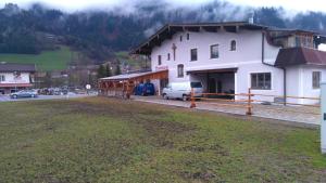 Un edificio blanco con una camioneta blanca estacionada enfrente. en Appartement Geisler, en Fügen