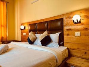 a bedroom with a large bed with a wooden headboard at Antriksh cottage Manali in Manāli +16 photos