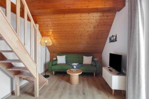 Una sala de estar con un sofá verde y un televisor. en Haus Freudig - Tannenblick, en Höchenschwand