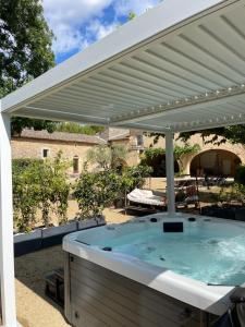 a hot tub under a white pergola at Cabane Perchée avec Jacuzzi, au Coeur du Luberon in Oppède