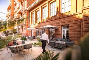 a man walking past a building with tables and chairs at Hotel Imperial - Liburnia in Opatija +37 photos