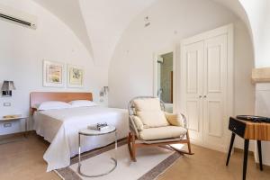 a bedroom with a bed and a chair and a table at Casa Portosalvo, Modica in Modica