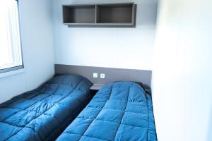 a bed in a room with a blue blanket at Mobile home confort - Fréjus - camping 4 étoiles - in Fréjus