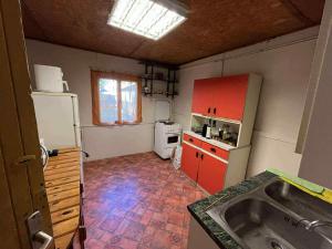 a kitchen with red cabinets and a white refrigerator at Zsófia faház in Vásárosnamény