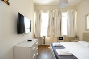 een slaapkamer met een wit bed en een flatscreen-tv bij Via Torino Apartment 3 in Milaan