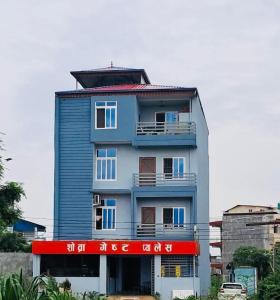 a tall blue building with a red sign on it at Shobra Guest Palace in Bākhri Kharka