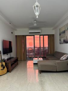 Una sala de estar con un sofá y un televisor de pantalla plana. en Sea view with balcony, en Bombay