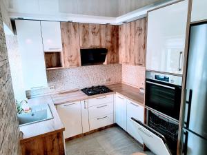a kitchen with white cabinets and a stove top oven at Krasnyi Mist in Chernihiv