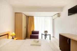 a hotel room with a bed and a purple chair at Hotel Venus in Mamaia