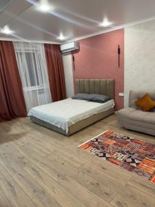a bedroom with a bed and a couch and a rug at Квартира in Balqash